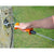 Hand using an orange gate handle with bungee cord gripper to tighten a wire on a wooden post with a grassy background