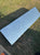 A gallagher livestock scale rectangular diamond-plate metal walkway platform  with a textured silver finish, shown outdoors on a patch of green and brown grass.